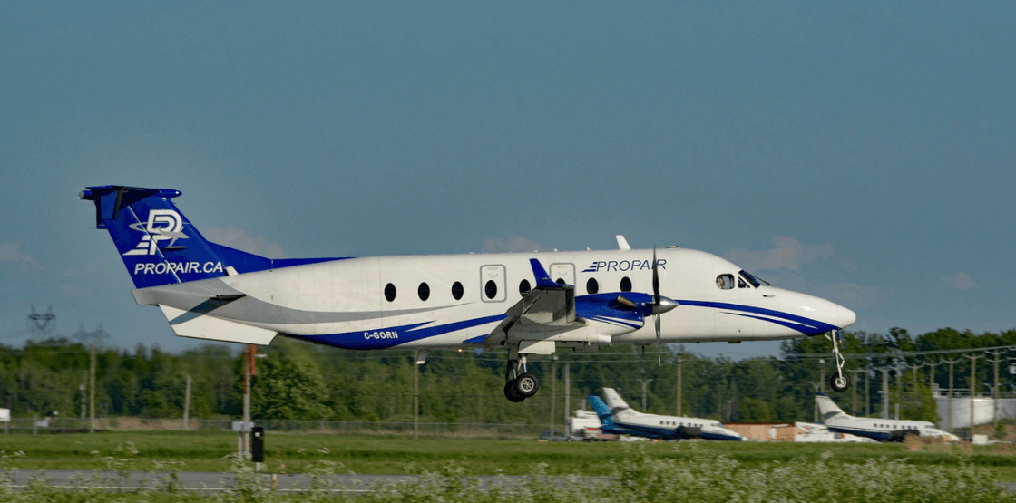 An image of Propair's B1900D taking off from a runway during the summer.