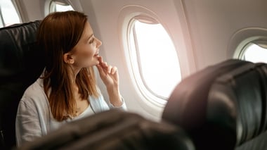 Propair - Une femme dans un avion qui regarde par le hublot